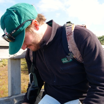 Kurt logging photographs and compass bearings at Rangitoto summit